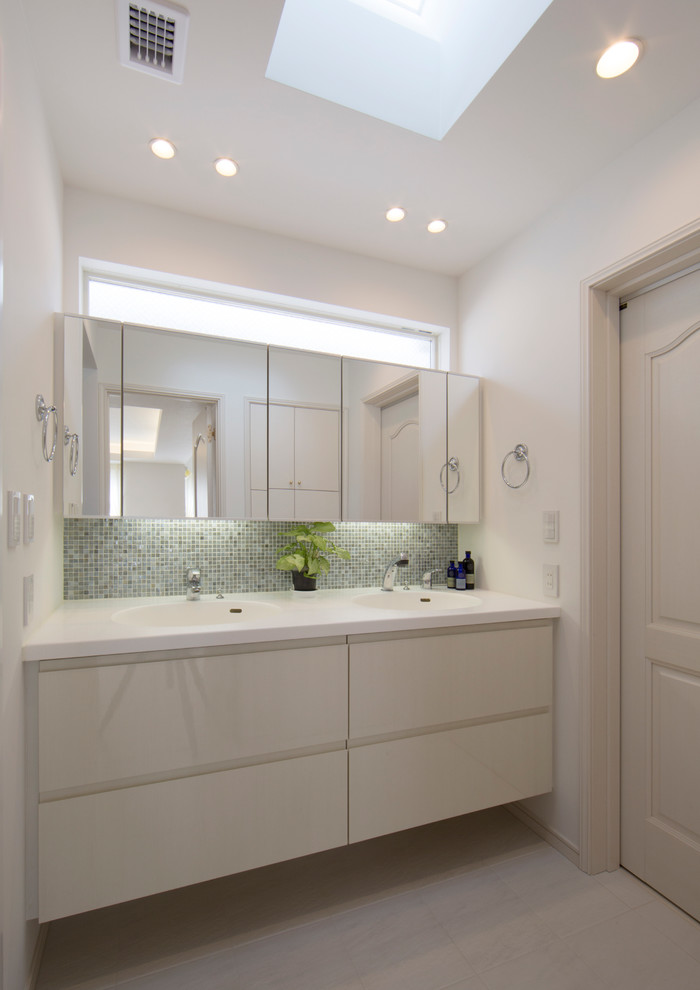 Foto di un bagno di servizio tradizionale di medie dimensioni con ante lisce, pareti bianche, lavabo integrato, ante beige, pavimento beige e piastrelle grigie