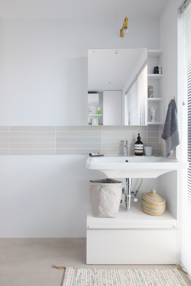 Example of a minimalist matchstick tile cement tile floor and gray floor powder room design in Tokyo with flat-panel cabinets, white cabinets, a one-piece toilet, white walls and a wall-mount sink