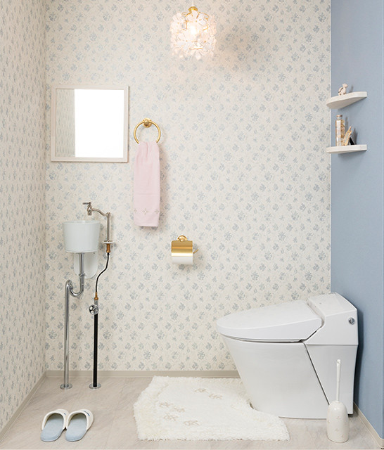 Nordisk inredning av ett litet vit vitt toalett, med en toalettstol med hel cisternkåpa, vita väggar, ett väggmonterat handfat och vitt golv