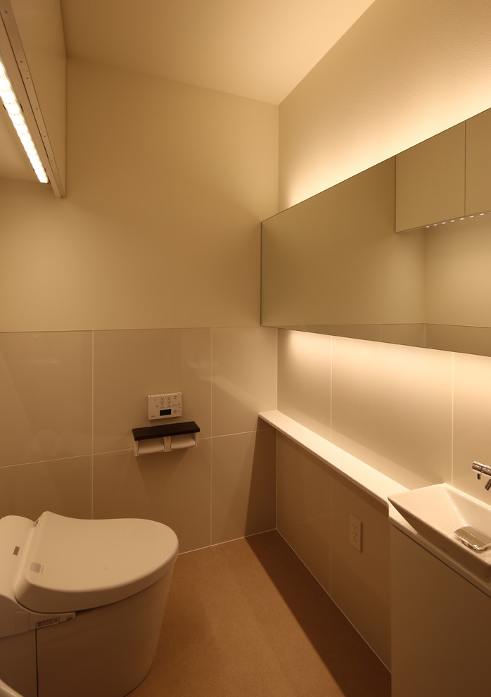 Mittelgroße Moderne Gästetoilette mit Kassettenfronten, weißen Schränken, Toilette mit Aufsatzspülkasten, weißer Wandfarbe, dunklem Holzboden, Unterbauwaschbecken, Mineralwerkstoff-Waschtisch, braunem Boden, weißer Waschtischplatte, beigen Fliesen und Marmorfliesen in Tokio