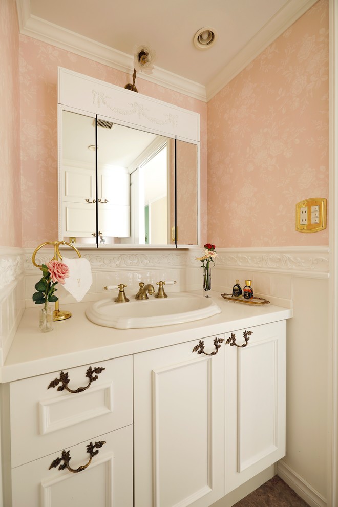 Foto di un bagno di servizio classico con ante con riquadro incassato, ante bianche, pareti rosa, lavabo da incasso e pavimento marrone