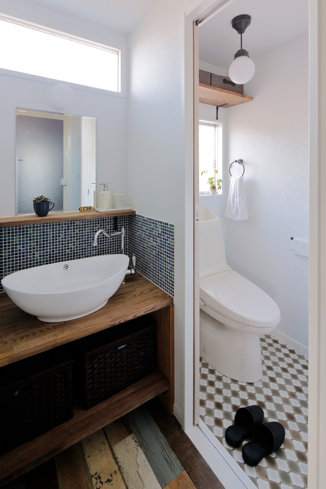 Nordische Gästetoilette mit offenen Schränken, weißer Wandfarbe, Aufsatzwaschbecken, Waschtisch aus Holz und brauner Waschtischplatte in Sonstige