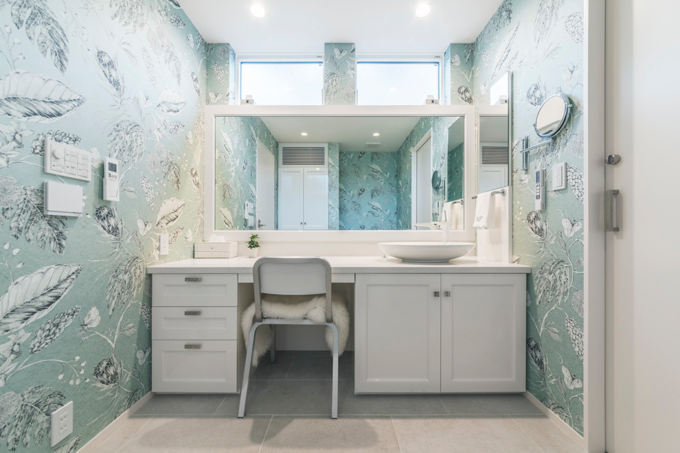 Inredning av ett klassiskt vit vitt toalett, med vita skåp, gröna väggar, beiget golv, luckor med infälld panel och ett fristående handfat