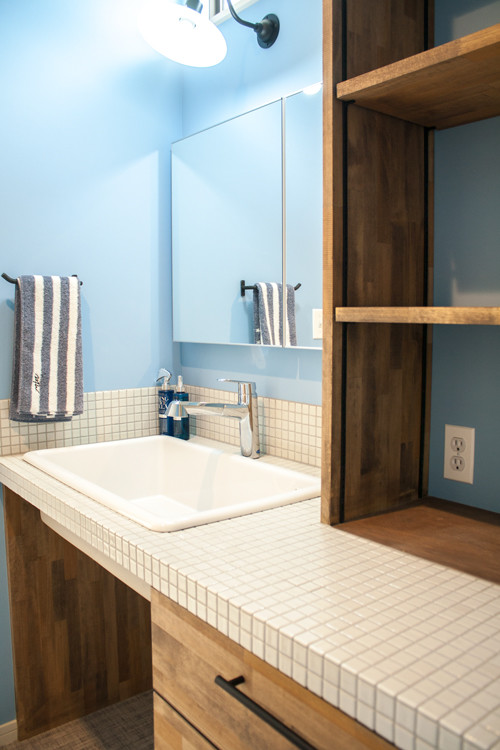 他の地域にある中くらいなラスティックスタイルのおしゃれなトイレ・洗面所 (白いタイル、青い壁、タイルの洗面台、白い洗面カウンター) の写真