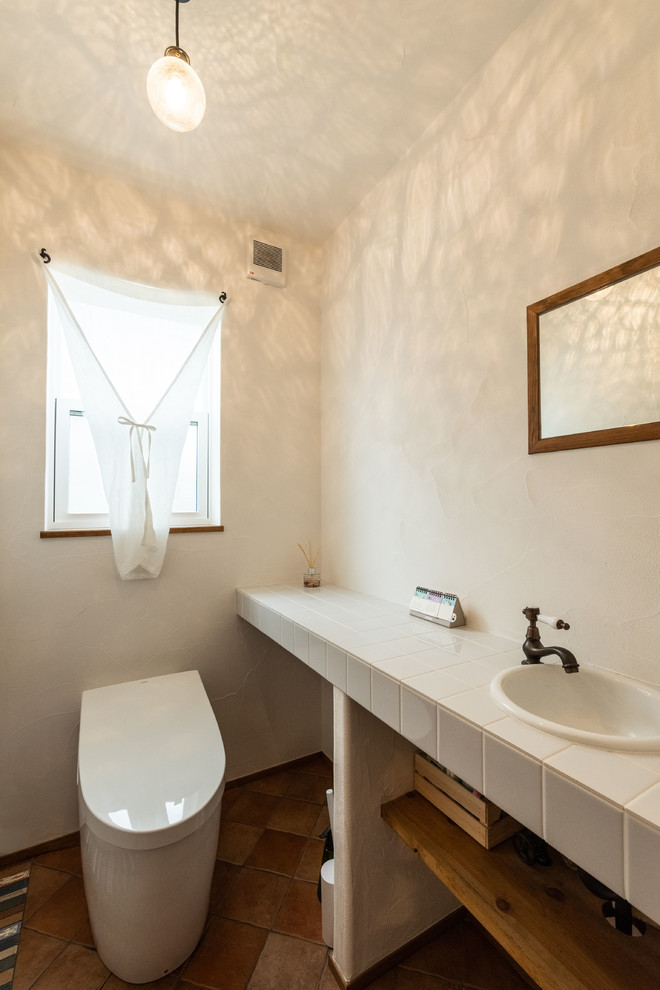 Modelo de aseo de estilo de casa de campo con paredes blancas, encimera de azulejos, suelo multicolor, encimeras blancas y lavabo encastrado