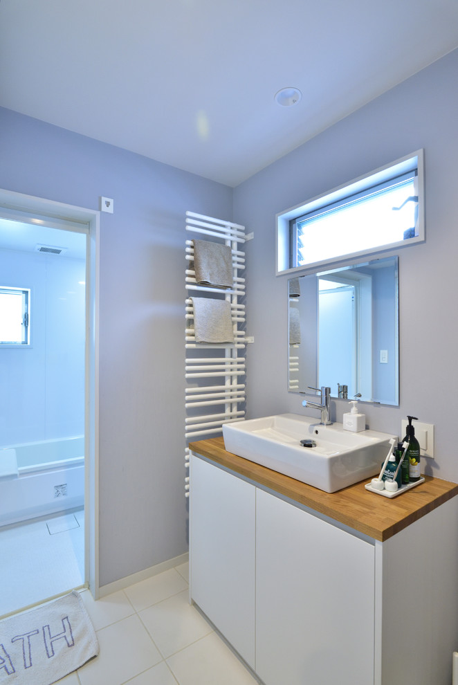 Ispirazione per un bagno di servizio moderno con ante lisce, ante bianche, pareti viola, lavabo a bacinella, top in legno, pavimento bianco e top marrone