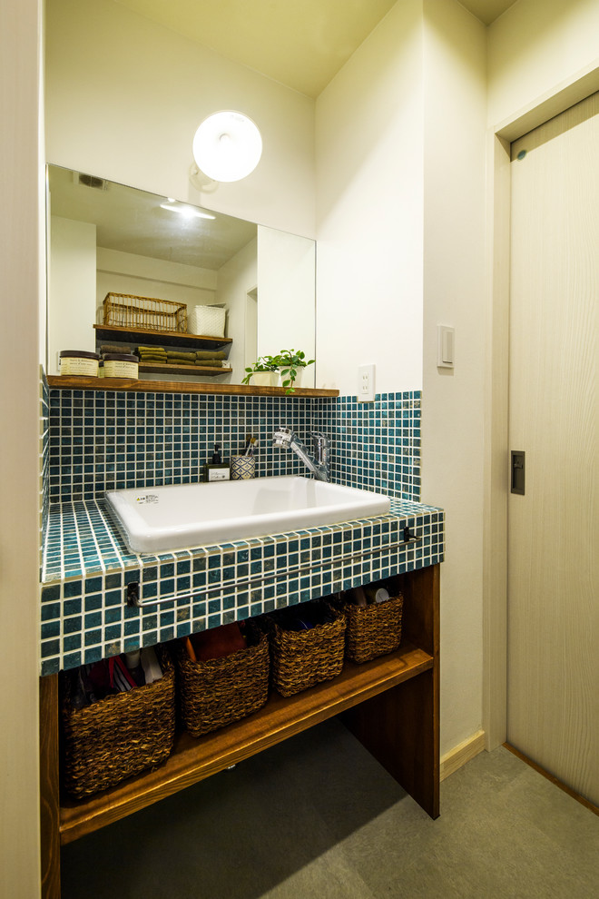 Foto di un bagno di servizio scandinavo con nessun'anta, pareti bianche, lavabo a bacinella, top piastrellato e pavimento grigio