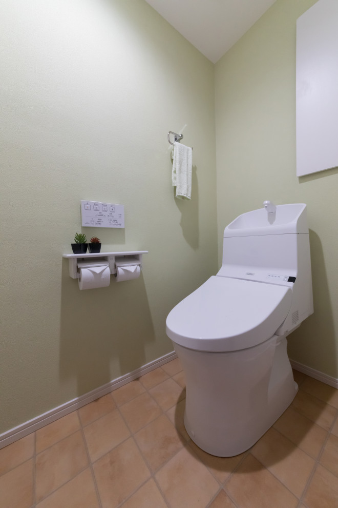 Aménagement d'un WC et toilettes moderne avec des portes de placard blanches, WC à poser, un mur vert et un sol en vinyl.