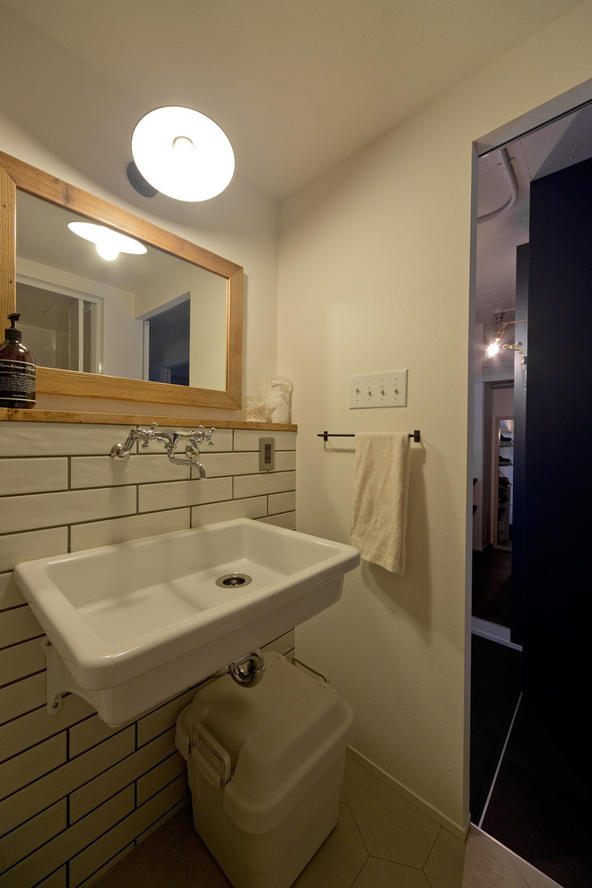 На фото: маленький туалет в стиле лофт с белой плиткой, серыми стенами, подвесной раковиной и серым полом для на участке и в саду