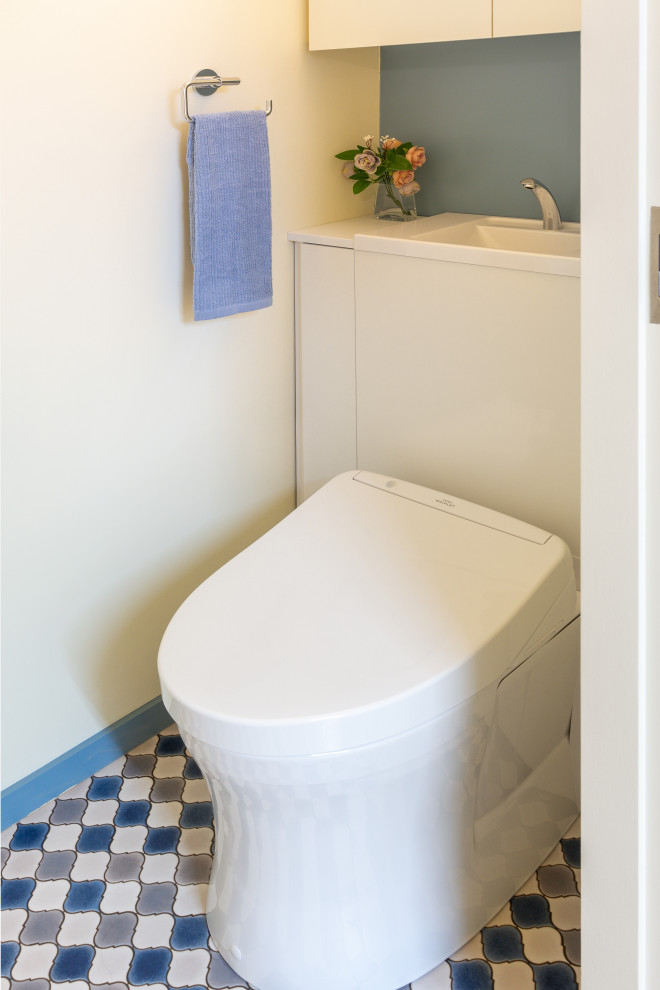 Inspiration for a small classic cloakroom in Tokyo with a two-piece toilet, blue walls, vinyl flooring, a built-in sink and multi-coloured floors.