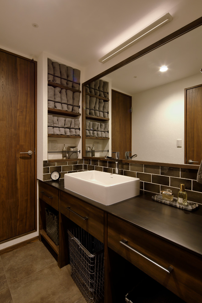 他の地域にあるミッドセンチュリースタイルのおしゃれなトイレ・洗面所 (フラットパネル扉のキャビネット、ヴィンテージ仕上げキャビネット、白い壁、ベッセル式洗面器、茶色い床) の写真