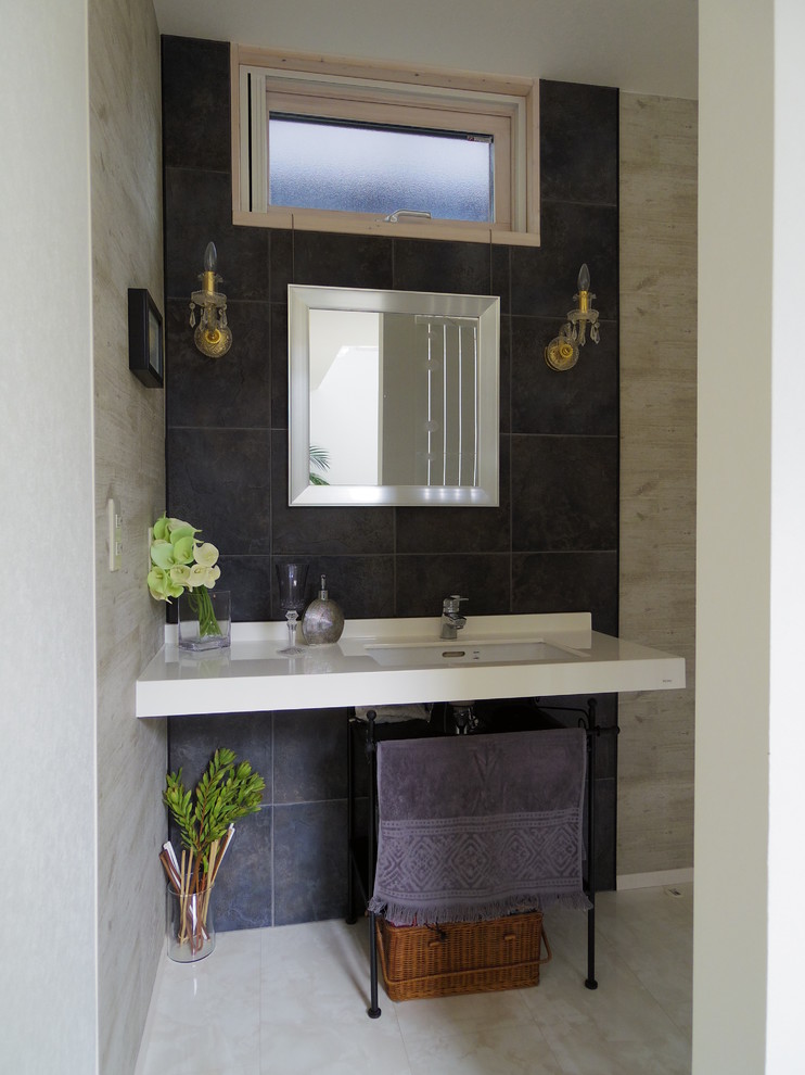 他の地域にあるコンテンポラリースタイルのおしゃれなトイレ・洗面所 (白い床、磁器タイル、グレーの壁、合板フローリング、壁付け型シンク、白い洗面カウンター) の写真