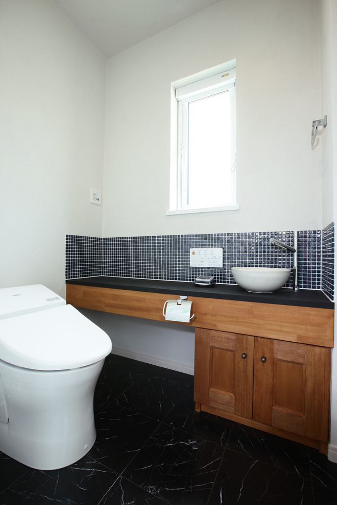 Idéer för minimalistiska toaletter, med luckor med infälld panel, skåp i mellenmörkt trä, vita väggar, ett fristående handfat och svart golv