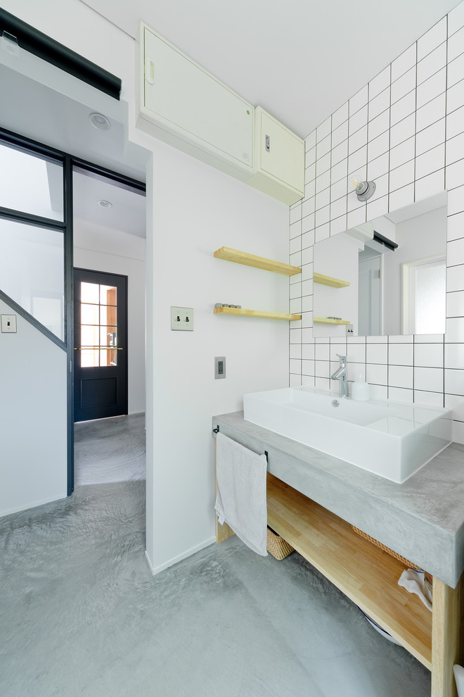 大阪にある中くらいなコンテンポラリースタイルのおしゃれなトイレ・洗面所 (オープンシェルフ、白いタイル、サブウェイタイル、白い壁、コンクリートの床、ベッセル式洗面器、コンクリートの洗面台、グレーの床) の写真