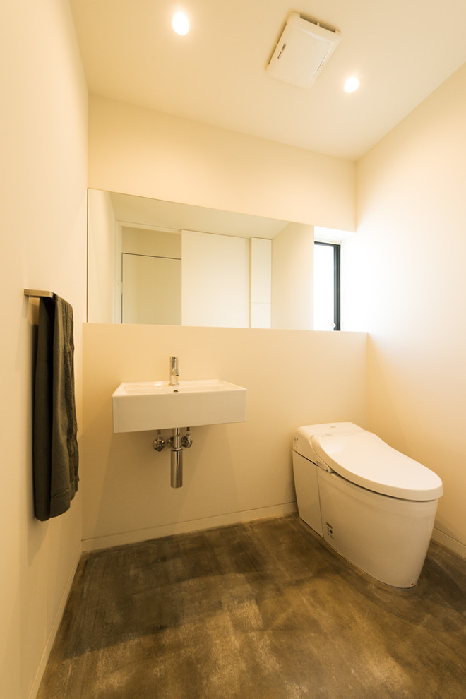 Exemple d'un WC et toilettes moderne avec un mur blanc, un lavabo suspendu et un sol gris.