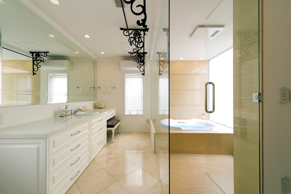 ヴィクトリアン調のおしゃれな浴室 (ドロップイン型浴槽、レイズドパネル扉のキャビネット、白いキャビネット、白い壁、オーバーカウンターシンク、ベージュの床) の写真