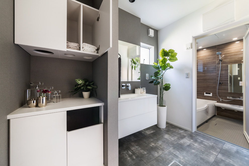 Cette image montre un WC et toilettes chalet avec un placard à porte plane, des portes de placard blanches, un mur gris et un sol gris.