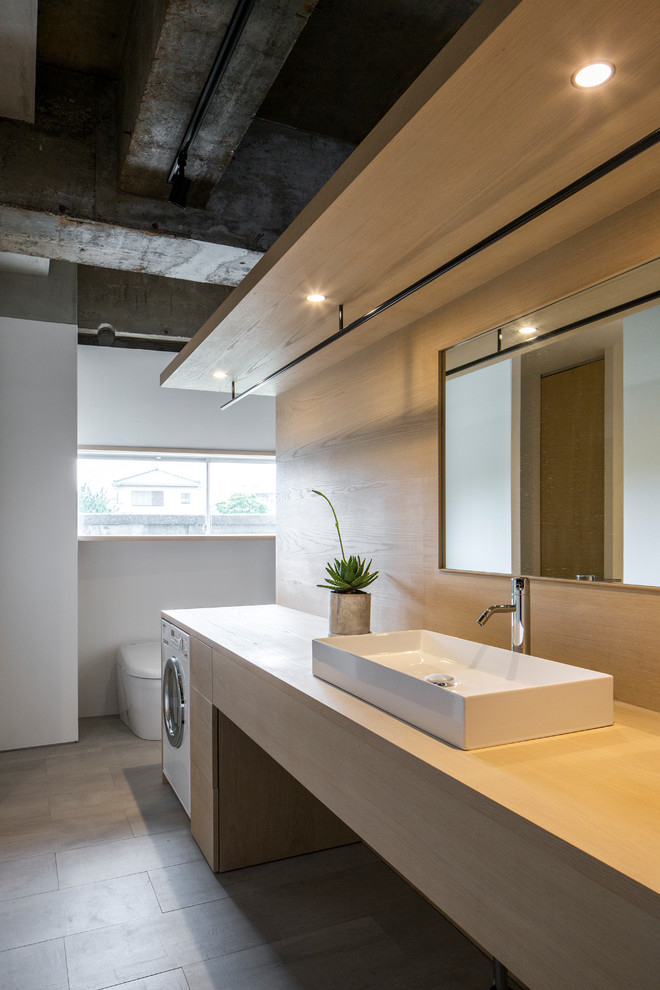 Industriell inredning av ett mellanstort beige beige toalett, med öppna hyllor, beige skåp, vita väggar, klinkergolv i porslin, träbänkskiva och grått golv