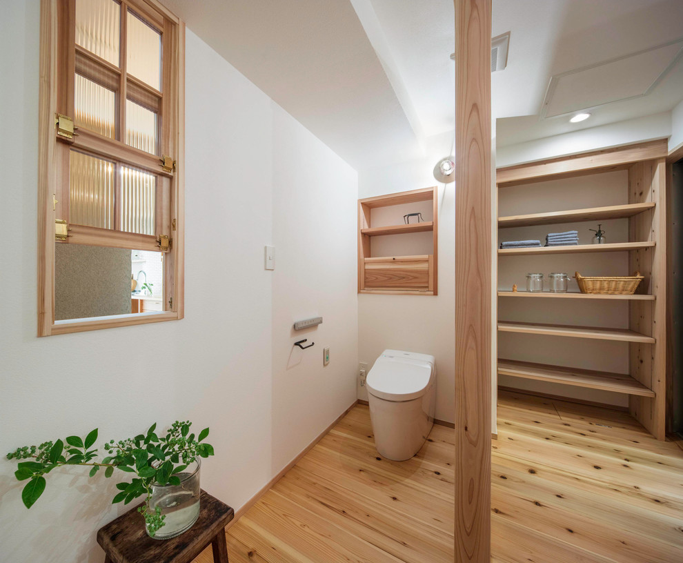 Diseño de aseo de estilo zen con paredes blancas, suelo de madera en tonos medios y suelo marrón
