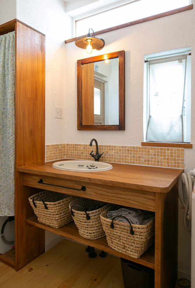 Réalisation d'un WC et toilettes champêtre avec un carrelage orange, un carrelage de pierre, un mur blanc, un plan de toilette en bois, un plan de toilette marron, un sol en bois brun, un lavabo posé et un sol marron.