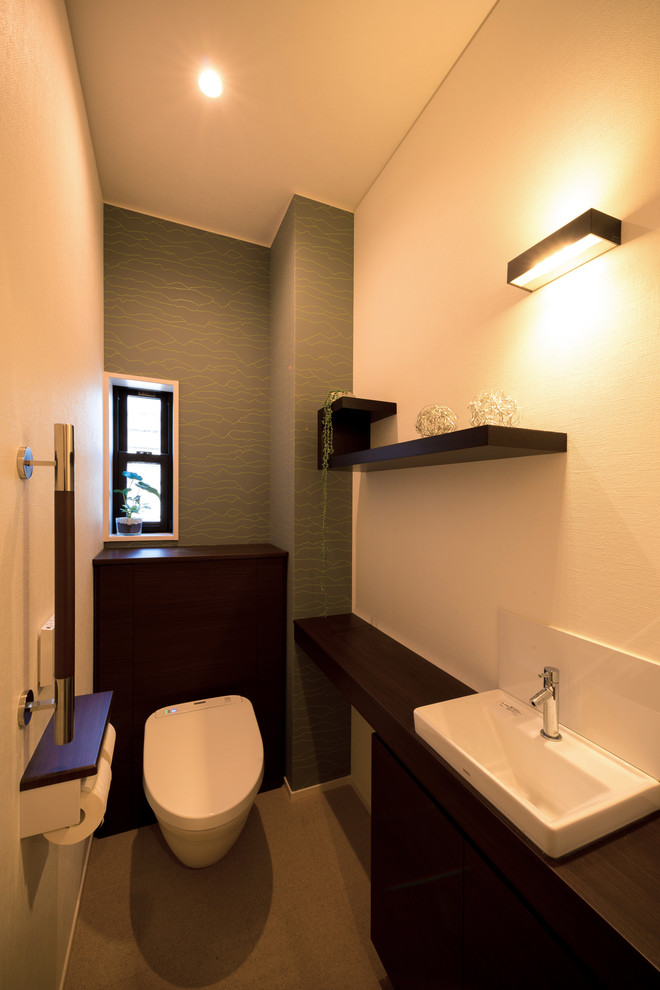 На фото: туалет в стиле модернизм с плоскими фасадами, темными деревянными фасадами, унитазом-моноблоком, белыми стенами, пробковым полом, накладной раковиной, столешницей из дерева и белым полом