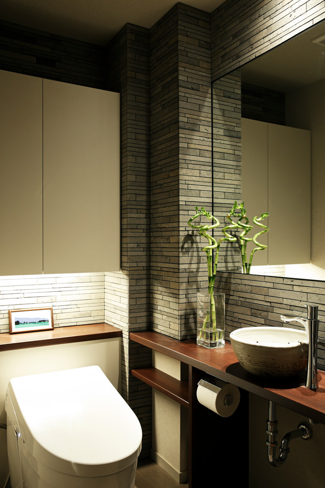 東京都下にあるコンテンポラリースタイルのおしゃれなトイレ・洗面所 (グレーの壁、ベッセル式洗面器) の写真