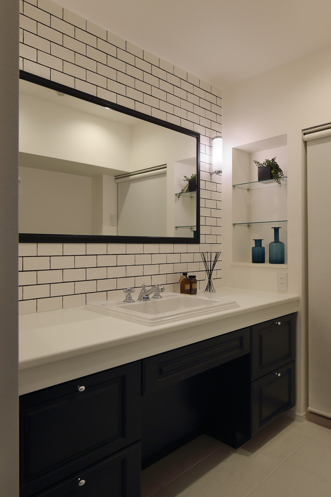 Cette image montre un WC et toilettes minimaliste en bois foncé de taille moyenne avec un placard avec porte à panneau encastré, un carrelage blanc, un mur blanc, un lavabo posé et un carrelage métro.