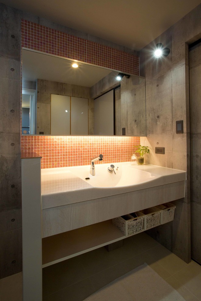 Idée de décoration pour un WC et toilettes urbain en bois foncé de taille moyenne avec un carrelage rose, un carrelage en pâte de verre, un mur gris, un sol en vinyl, un lavabo intégré, un plan de toilette en surface solide, un sol beige et un plan de toilette blanc.