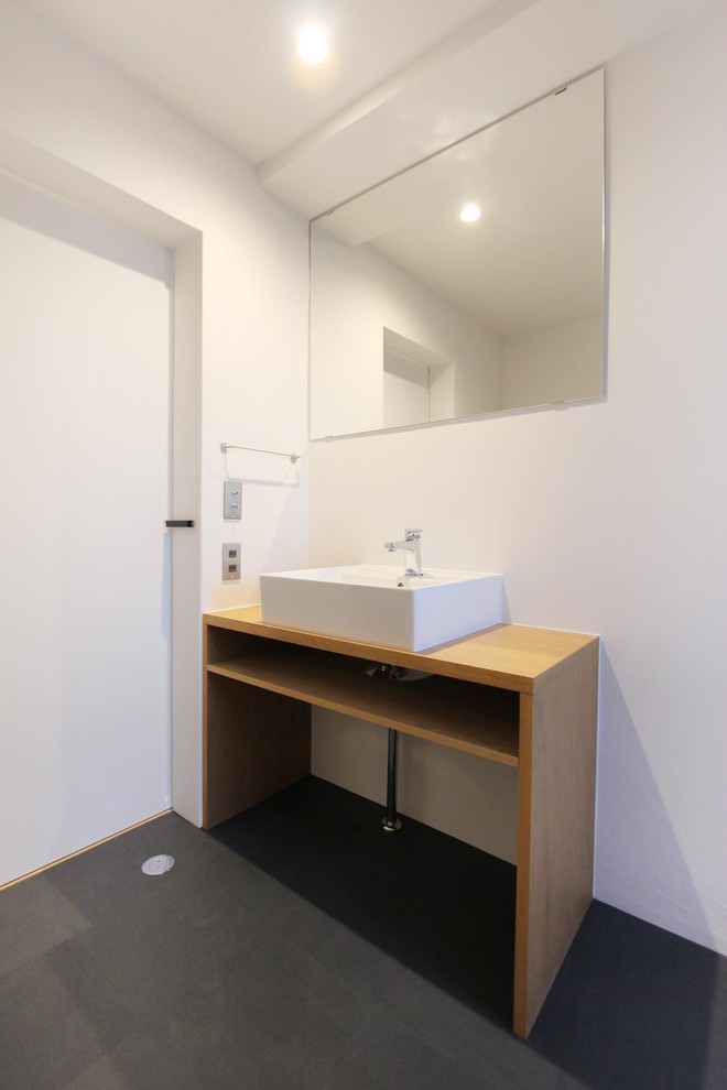 Cette photo montre un WC et toilettes industriel avec un mur blanc, une vasque et un sol gris.