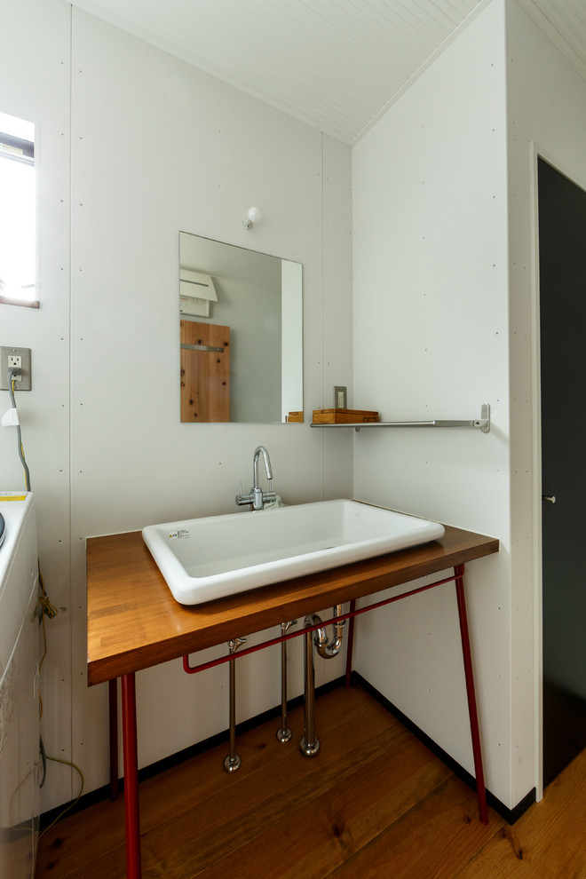 Immagine di un bagno di servizio industriale con WC monopezzo, pareti bianche e lavabo a consolle