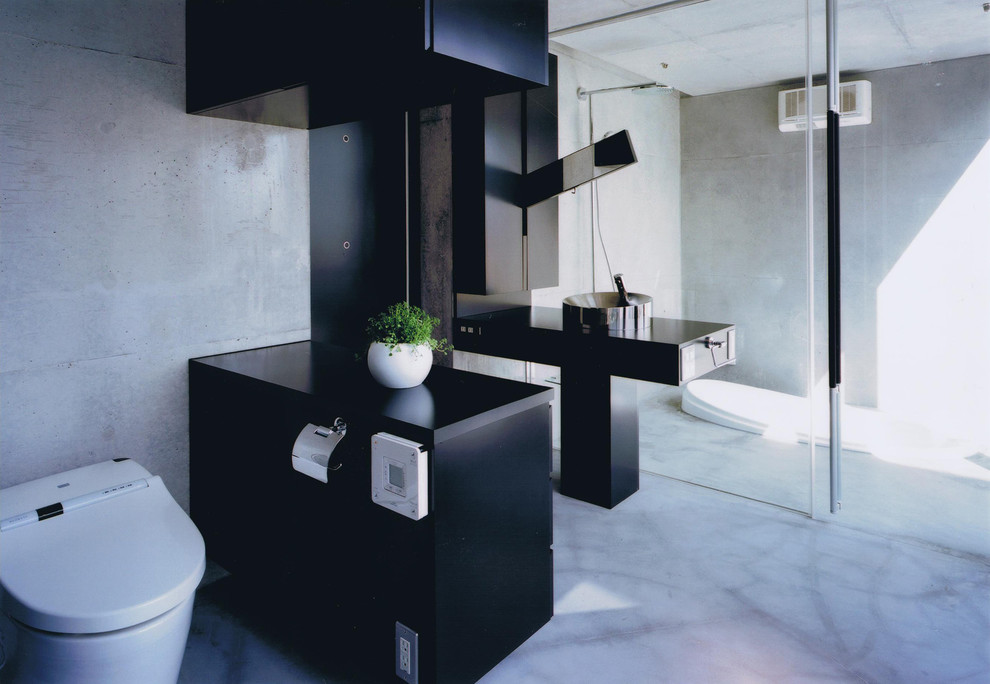 他の地域にあるコンテンポラリースタイルのおしゃれなトイレ・洗面所 (黒いキャビネット、グレーの壁、ベッセル式洗面器、グレーの床、黒い洗面カウンター) の写真