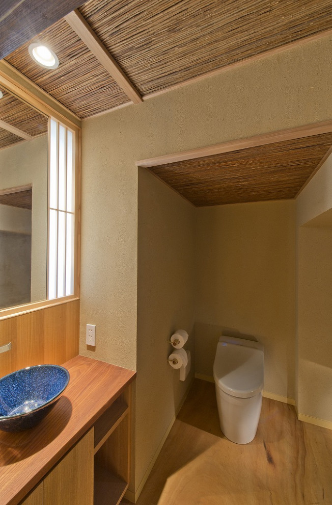 Стильный дизайн: туалет среднего размера в классическом стиле с фасадами островного типа, искусственно-состаренными фасадами, унитазом-моноблоком, бежевыми стенами, настольной раковиной, столешницей из дерева, бежевым полом, бирюзовой столешницей, встроенной тумбой и деревянным потолком - последний тренд