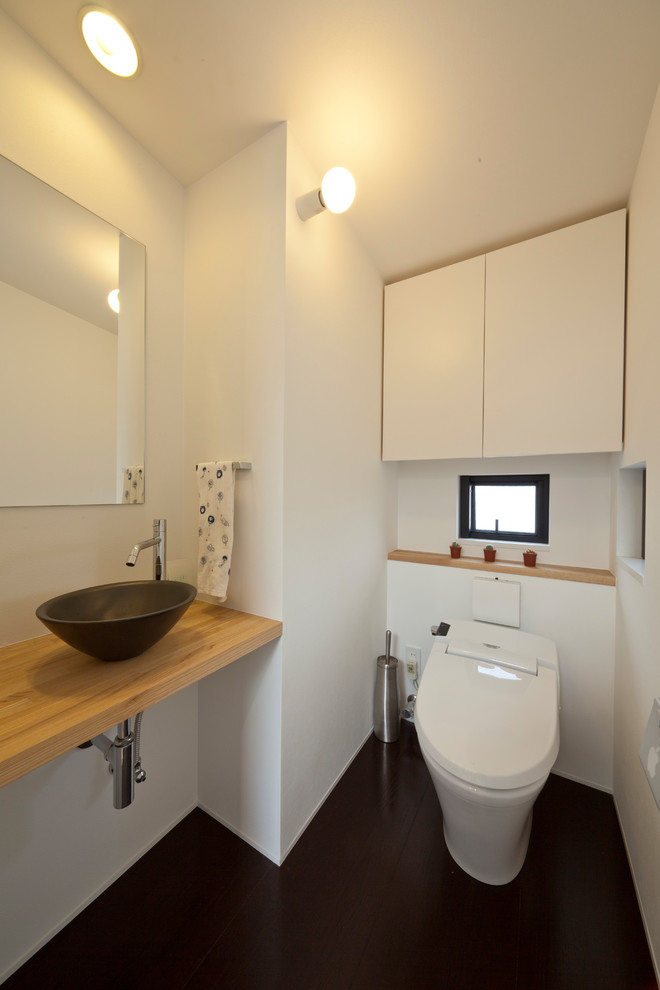 Foto de aseo contemporáneo con paredes blancas, lavabo sobreencimera, encimera de madera, suelo negro y encimeras marrones