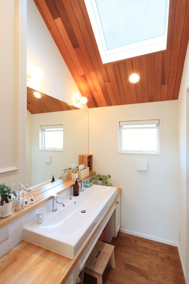 World-inspired cloakroom in Other with white cabinets, mosaic tiles, white walls, medium hardwood flooring, a trough sink, wooden worktops, brown floors and brown worktops.