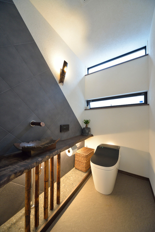 На фото: туалет с разноцветными стенами, настольной раковиной, серым полом и унитазом-моноблоком