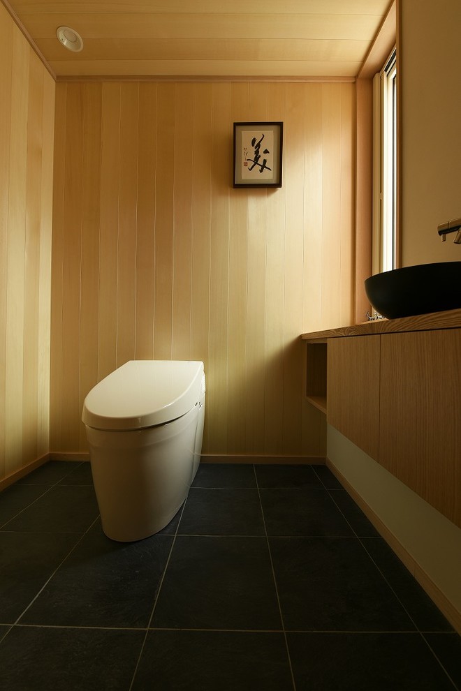 На фото: туалет среднего размера в восточном стиле с светлыми деревянными фасадами с