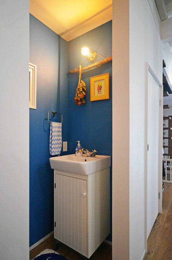 大阪にある小さなモダンスタイルのおしゃれなトイレ・洗面所 (青い壁、無垢フローリング、ベッセル式洗面器、茶色い床) の写真