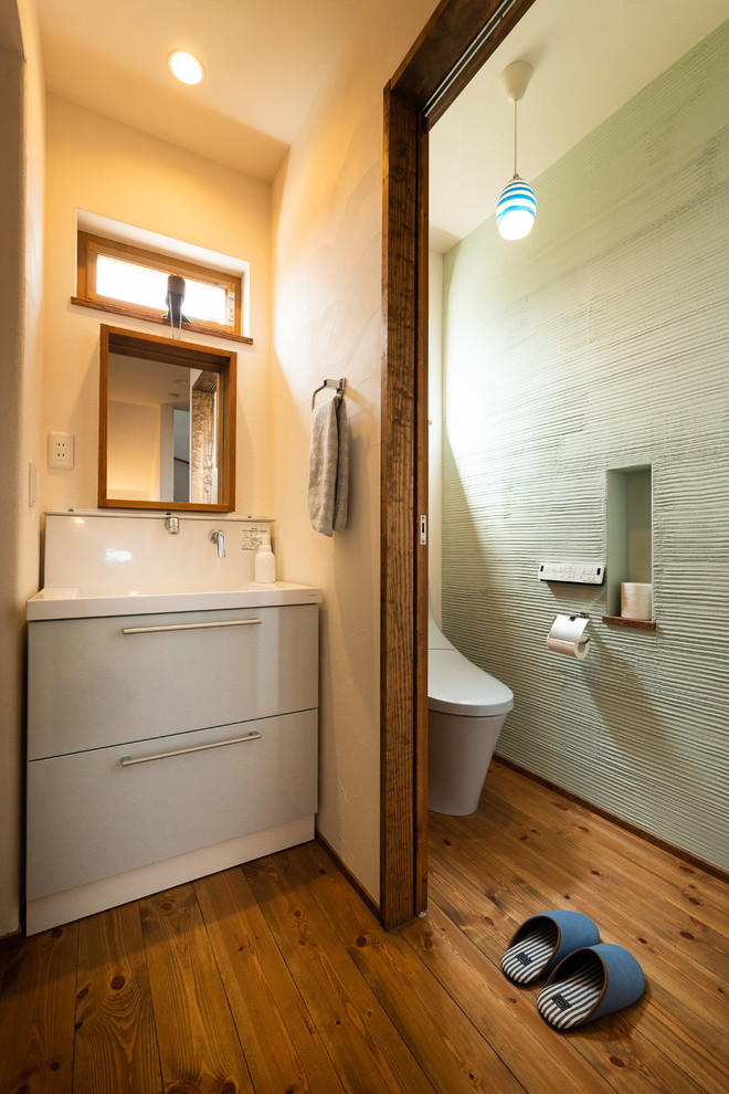 Пример оригинального дизайна: туалет в восточном стиле с паркетным полом среднего тона, синими фасадами, разноцветными стенами, монолитной раковиной и коричневым полом