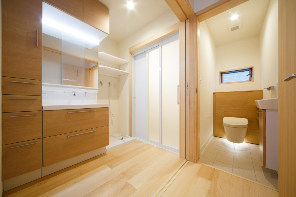Réalisation d'un WC suspendu nordique de taille moyenne avec des portes de placard beiges, un mur beige, parquet clair, un lavabo intégré et un plan de toilette marron.
