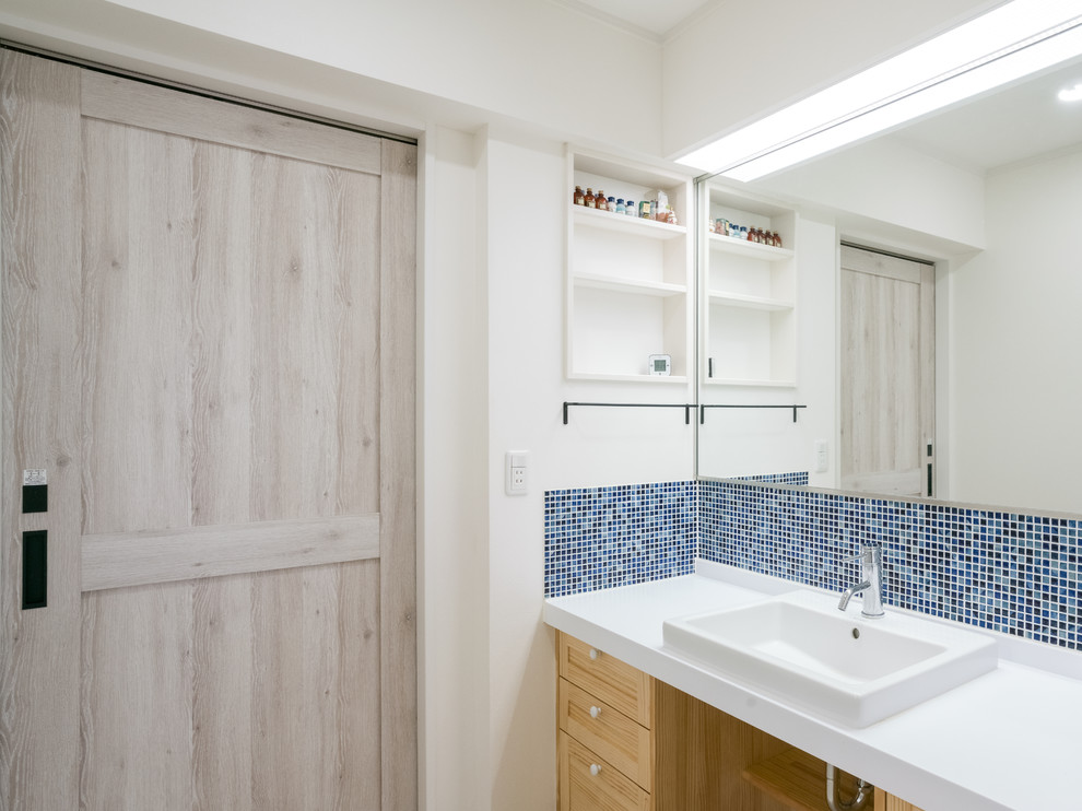 Inspiration for a small rural cloakroom in Other with recessed-panel cabinets, light wood cabinets, white walls, a built-in sink, blue tiles, mosaic tiles, solid surface worktops and white worktops.