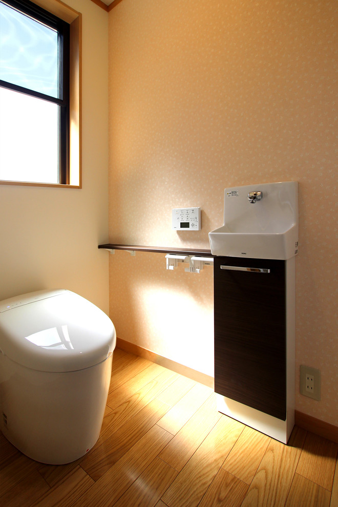 Idée de décoration pour un petit WC et toilettes minimaliste avec WC à poser, un mur rose, un sol en contreplaqué et un sol beige.