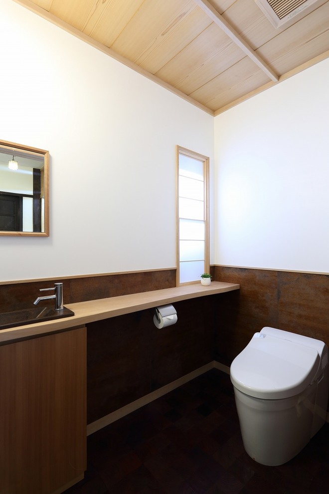 Cette image montre un WC et toilettes asiatique en bois brun de taille moyenne avec un placard à porte plane, un mur multicolore, un lavabo posé et un sol marron.