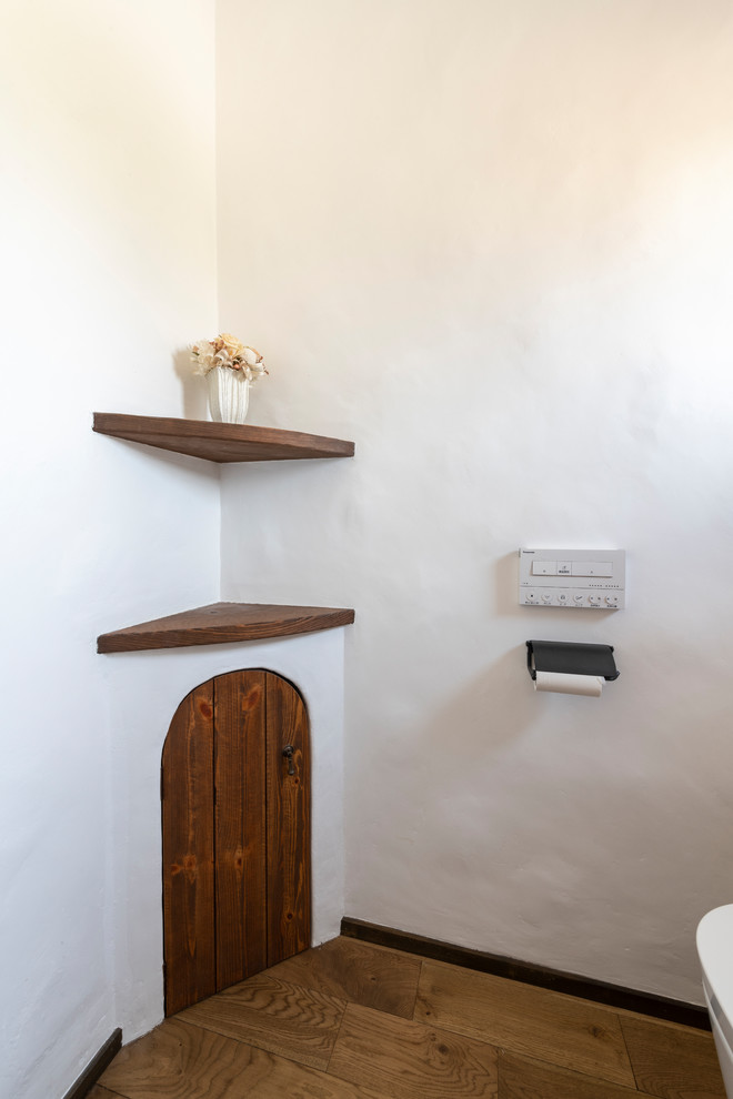 Inspiration for a small mediterranean cloakroom in Other with brown cabinets, a one-piece toilet, white walls, dark hardwood flooring, a built-in sink, wooden worktops, brown floors and brown worktops.