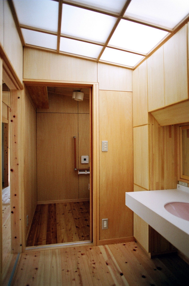 Esempio di un piccolo bagno di servizio minimal con WC monopezzo, pareti bianche, parquet chiaro e top bianco