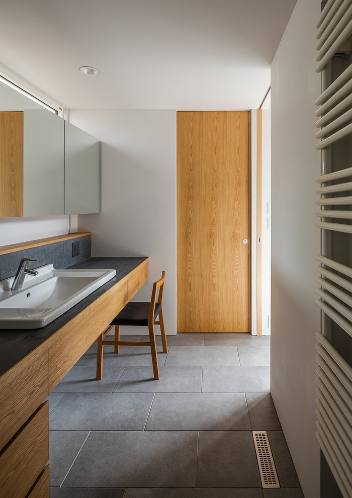 Moderne Gästetoilette mit flächenbündigen Schrankfronten, braunen Schränken, weißer Wandfarbe, Einbauwaschbecken und schwarzem Boden in Sonstige