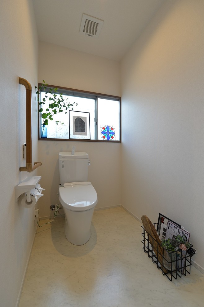 Inredning av ett asiatiskt stort toalett, med vita väggar och beiget golv