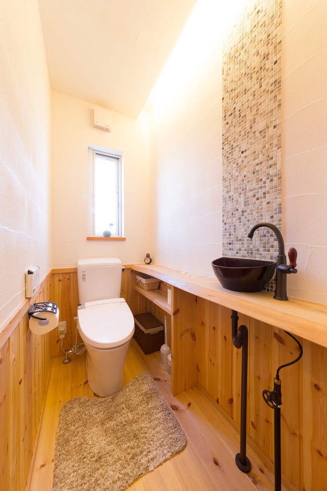 Immagine di un bagno di servizio etnico con pareti multicolore, pavimento in legno massello medio, lavabo a bacinella e pavimento marrone