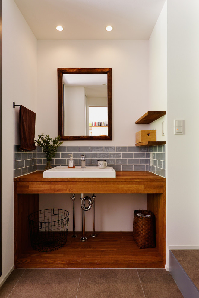 Aménagement d'un WC et toilettes scandinave avec un mur blanc, une vasque, un sol gris et un plan de toilette marron.