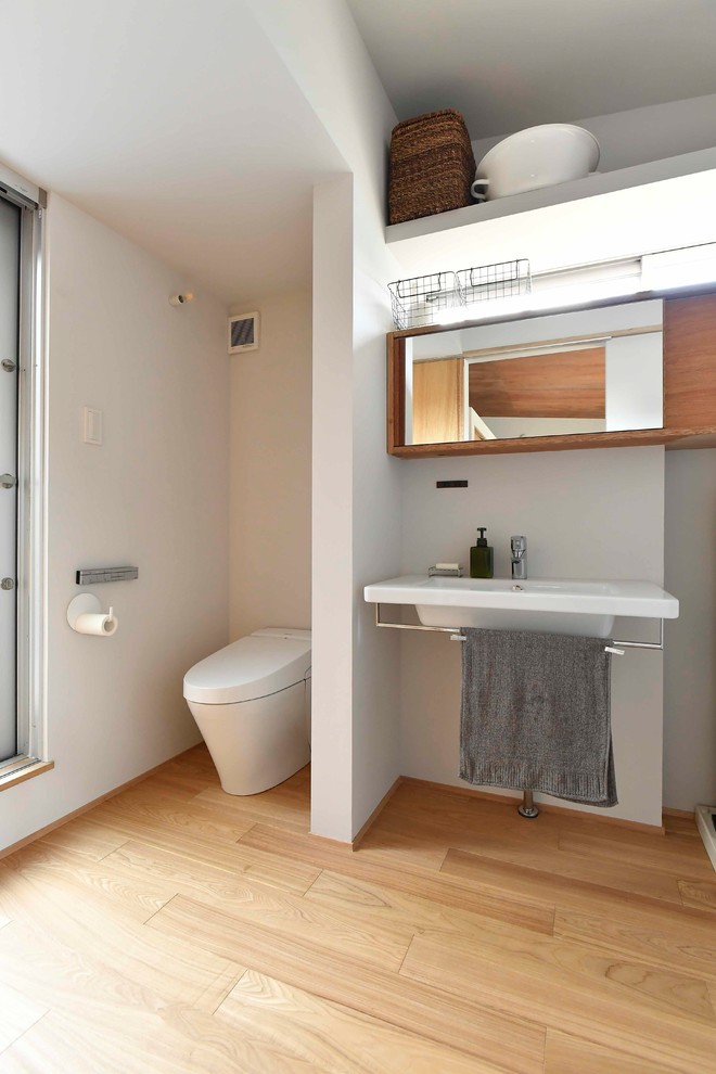 他の地域にある北欧スタイルのおしゃれなトイレ・洗面所 (オープンシェルフ、白い壁、淡色無垢フローリング、コンソール型シンク、ベージュの床) の写真