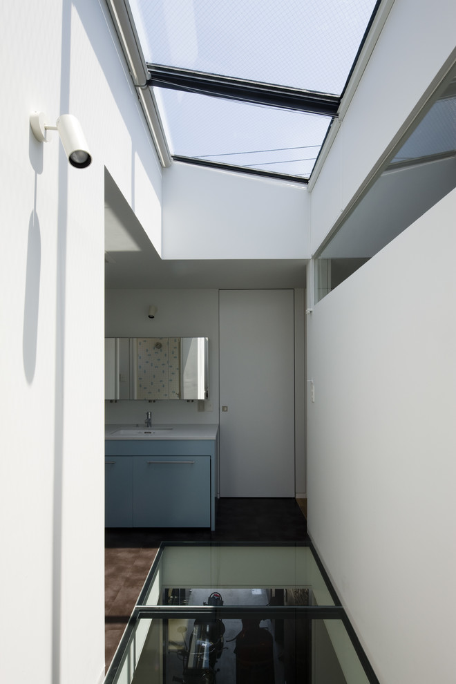 Inspiration for a medium sized modern cloakroom in Other with flat-panel cabinets, turquoise cabinets, white tiles, white walls, vinyl flooring, a submerged sink, solid surface worktops, brown floors and grey worktops.